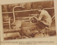 873673 Afbeelding van een machinist die de drijfstangen van een stoomlocomotief oliet, bij de locomotievenloods op het ...